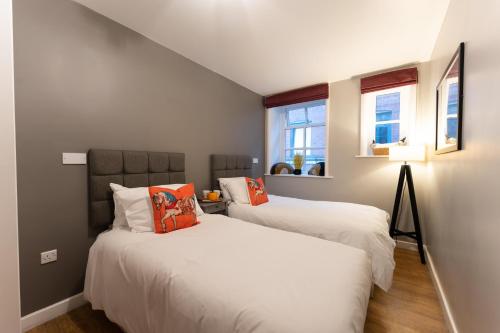 two beds in a small room with two windows at High Street Town House in Manchester