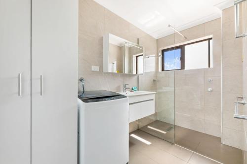 a white bathroom with a sink and a shower at Apollo Unit 21 1st Floor in Narooma