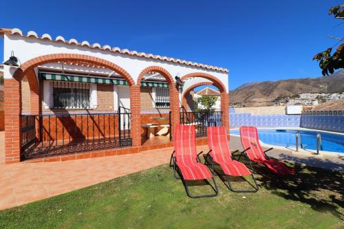 un grupo de sillas rojas sentadas en el césped junto a una piscina en Villa los Olivos Spainsunrentals 1210, en Nerja