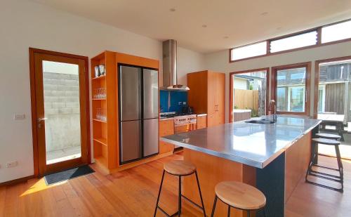 una cocina con una gran isla con dos taburetes en The Beach House Raumati, en Paraparaumu