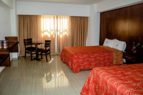a hotel room with two beds and a table and chairs at Hotel RRU Puebla in Puebla