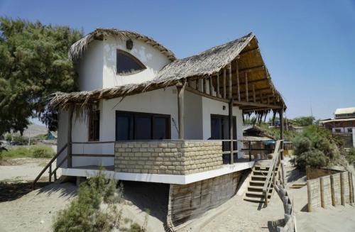a small house with a thatched roof on the beach at Mancora Soul in Máncora