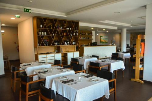 a dining room with white tables and chairs in a restaurant at Belmonte Sinai Hotel in Belmonte