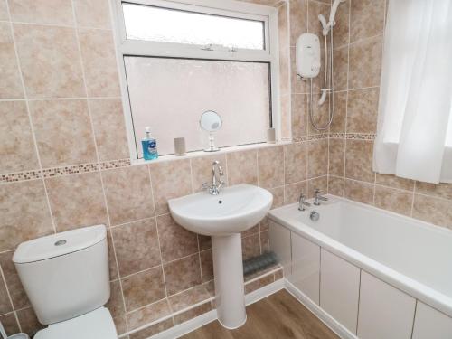 a bathroom with a sink and a toilet and a bath tub at Victoria Cottage in Amble