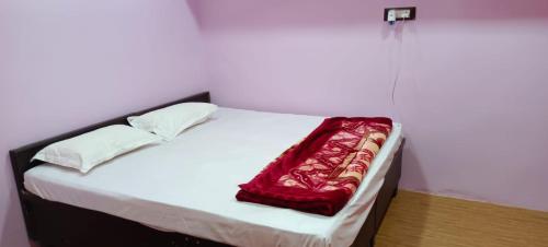 a bed with a red blanket on top of it at Govind Niwas Homestay in Jagdalpur