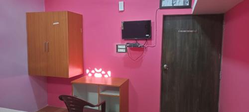 a room with a pink wall with a desk and a tv at Govind Niwas Homestay in Jagdalpur