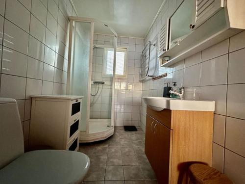 een kleine badkamer met een wastafel en een douche bij Stort hus med trädgård - sjötomt med egen båt 