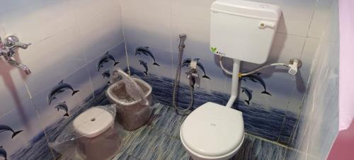 La salle de bains est pourvue de toilettes avec des dauphins peints sur le mur. dans l'établissement Govind Niwas Homestay, à Jagdalpur