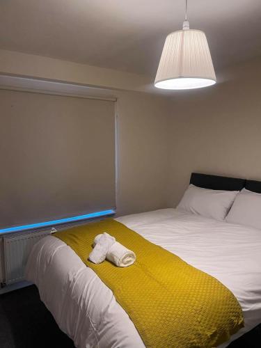 uma cama com um cobertor amarelo e uma toalha em Shelly's Place em Glasgow