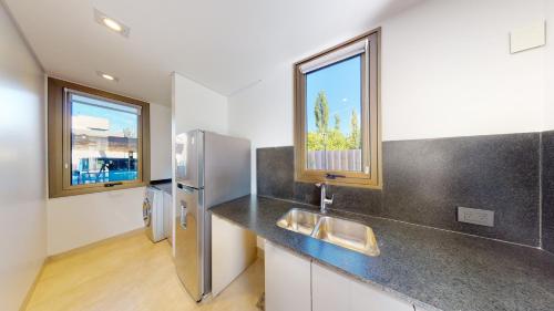 a kitchen with a sink and a refrigerator at Liniers Green Apartments in Chacras de Coria