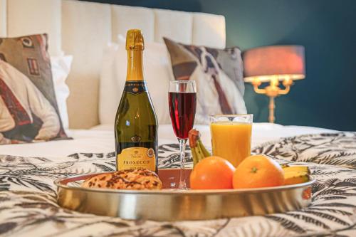 een fles wijn en een dienblad met eten en drinken op een bed bij Luxury 4 Bedroom House - Close to M1 - Free Parking, Fast Wifi, SmartTV with Netflix by Yoko Property in Milton Keynes