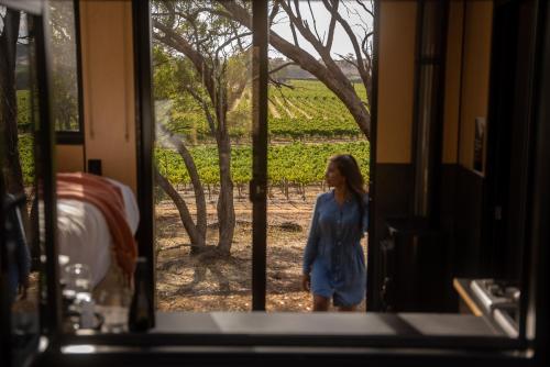 uma menina parada do lado de fora de uma porta olhando para uma vinha em CABN Off Grid Cabins Barossa em Seppeltsfield