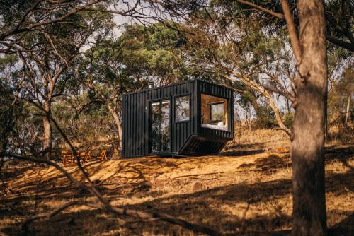 a black box tiny house on a hill in the woods at CABN Off Grid Cabins Barossa in Seppeltsfield