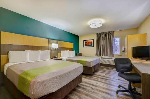 a hotel room with two beds and a desk at Studio 6 Lenexa - Overland Park in Lenexa