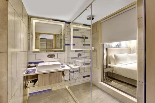 uma casa de banho com uma cama, um lavatório e um espelho. em Park Inn by Radisson Surat em Surat