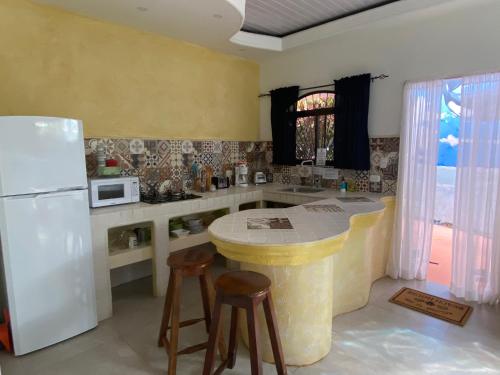 a kitchen with a white refrigerator and a counter with stools at Casa Maiana in Sámara