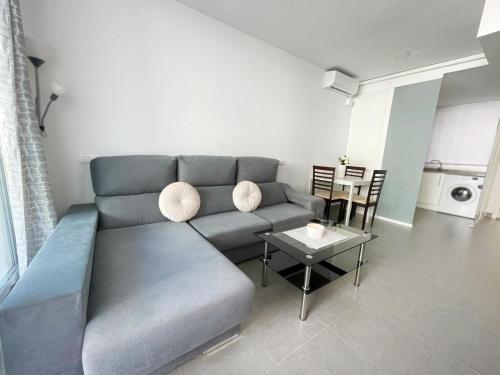 ein Wohnzimmer mit einem blauen Sofa und einem Tisch in der Unterkunft Apartamentos Novacala Benidorm in Cala de Finestrat