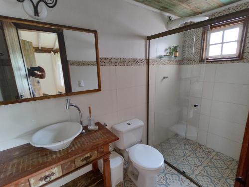 uma casa de banho com um WC, um lavatório e um espelho. em Casa Moitará em Tiradentes