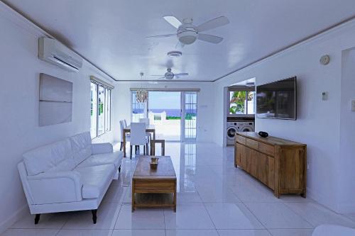 Una sala de estar con un sofá blanco y un televisor. en Stunning Ocean View, en Negril