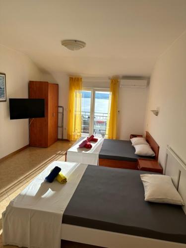 een hotelkamer met 2 bedden en een televisie bij Apartments Badnje in Dramalj