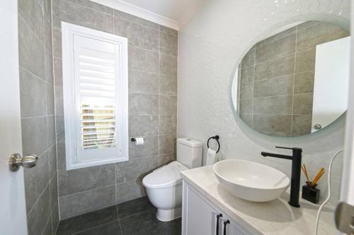 a bathroom with a toilet and a sink and a mirror at Charming 6 BRM Villa in Melbourne Mullum Mullum Precinct in Doncaster East