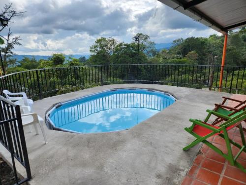 a swimming pool with two chairs and a fence at CASA DE CAMPO CORRALEJAS - ANOLAIMA in Anolaima