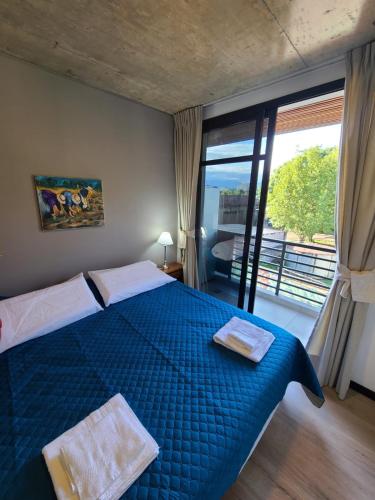 1 dormitorio con cama azul y ventana grande en Departamento - Salta Capital cg - Edificio Usina en Salta