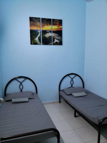 twee bedden in een kamer met een blauwe muur bij MIZU Homestay Melaka in Melaka