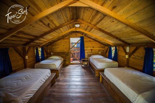 a room with three beds in a wooden cabin at Tapas & Surf in Petacaltepe