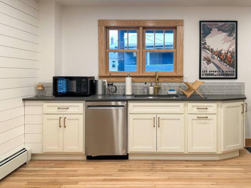 a kitchen with white cabinets and a sink and a microwave at Hÿgge House in Margaretville