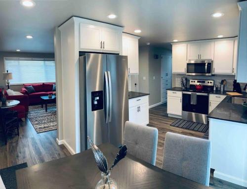 uma cozinha com um frigorífico de aço inoxidável e uma sala de estar em Beautiful, well-stocked home - sleeps 7! em Yakima