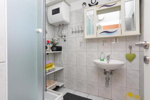 een kleine badkamer met een wastafel en een spiegel bij Apartments by the sea Rastici, Ciovo - 9717 in Trogir