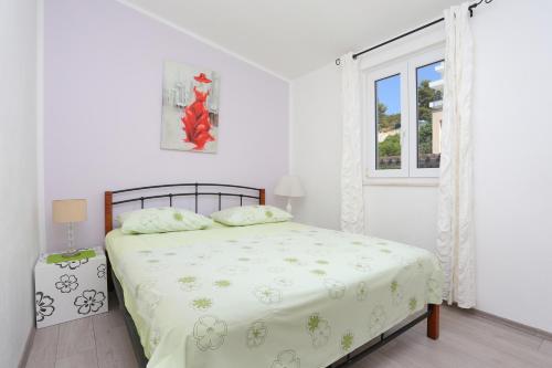 een witte slaapkamer met een bed en een raam bij Apartments by the sea Rastici, Ciovo - 9717 in Trogir