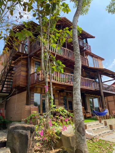 a wooden house with trees and flowers in front of it at Floor river view in Cat Tien