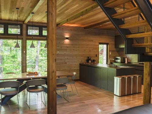 a kitchen and dining room of a cabin with wooden walls at Hygge Chalet Hakuba in Hakuba