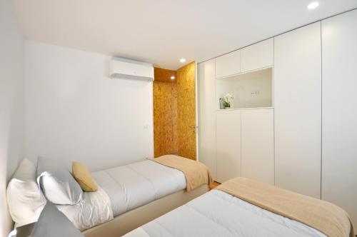 two beds in a small room with white walls at Casa do Bieira for Family By Sé Apartamentos in Braga