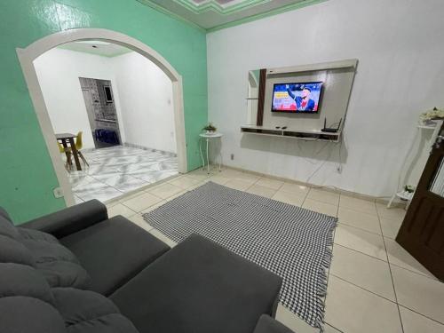 sala de estar con sofá y TV de pantalla plana en Casa térrea a 2 min da praia dos anjos, en Arraial do Cabo