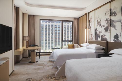 um quarto de hotel com duas camas e uma grande janela em Sheraton Yunfu Xinxing Hotel em Yunfu