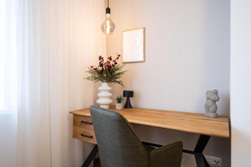 a desk with a vase of flowers and a chair at MH Living - 23 - Scandinavian Living Dream in Center in Graz