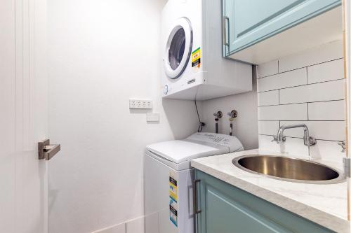 a small bathroom with a sink and a washing machine at Bay Parklands, 36 2 Gowrie Avenue - close to the water with Air con, WiFi, pool & spa & tennis court in Shoal Bay