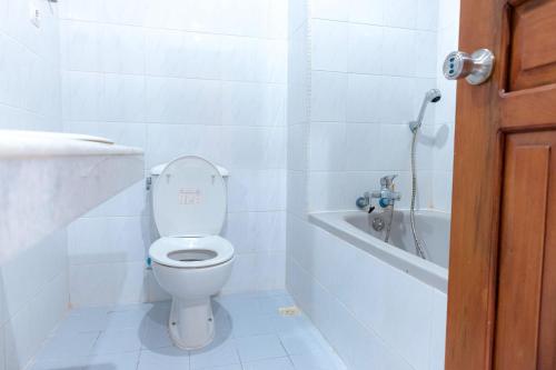 a white bathroom with a toilet and a bath tub at Capital O 93602 Hotel Tempoa Inn in Jambi