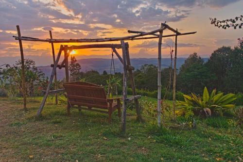 a bench under a gazebo with the sunset in the background at Villa Namaste - Cabaña Albores in Curití