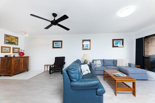 a living room with a blue couch and a ceiling fan at Braemar 6 in Forster