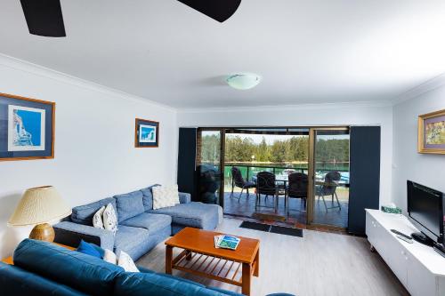 a living room with a blue couch and a television at Braemar 6 in Forster