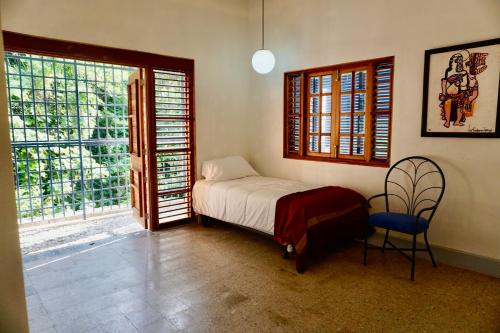 a bedroom with a bed and a chair and windows at Gordon Town Kotch in Kingston