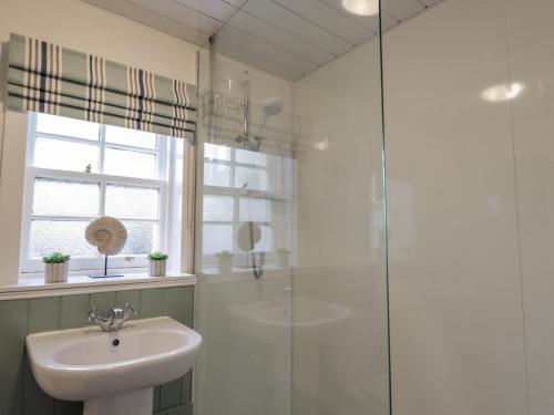 a bathroom with a sink and a glass shower at Craggan Cottage - Balmacara in Coillemore