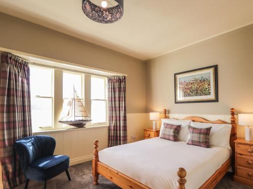a bedroom with a bed and a chair and a window at Ferry Cottage - Balmacara in Coillemore