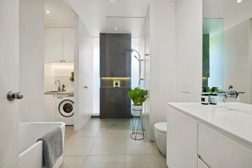 a white bathroom with a sink and a toilet at St Kilda Style - Stunning 3 Bedroom House in Melbourne