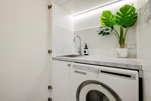 a white laundry room with a sink and a washing machine at St Kilda Style - Stunning 3 Bedroom House in Melbourne