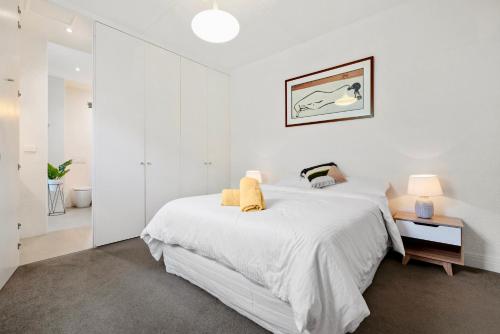 a white bedroom with a large bed with white sheets at St Kilda Style - Stunning 3 Bedroom House in Melbourne